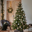 Decorated artificial Christmas tree styled with baubles, warm white lights and seasonal ornaments, creating an elegant Christmas living room display.