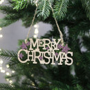 A gold 'Merry Christmas' sign with pink stars, hanging from a Christmas tree branch.