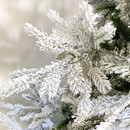 Detailed view of frosted artificial pine branches coated with realistic white flocking to recreate the look of a freshly snow-covered Christmas tree.