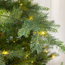 Close-up of realistic evergreen branches illuminated with warm white LED lights, creating a cosy Christmas ambience.