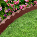 Green grass bordered by a scalloped brown edge. Bright pink flowers and lush greenery in the background create a vibrant, cheerful garden scene.