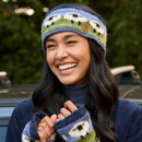 Smiling woman wearing a colourful knitted headband and matching mittens stands outdoors. She exudes joy and warmth with a background of greenery. Smiling woman wearing a colourful knitted headband and matching mittens stands outdoors. She exudes joy and warmth with a background of greenery.