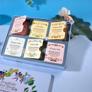 A colorful tea box set with six different labels: Beautiful Me, Pure Me, Happy Me, Sleepy Me, Calm Me, and Shape Me. Floral designs decorate each label, conveying a serene and inviting mood. A delicate rose and leaves sit in the background, enhancing the botanical theme.