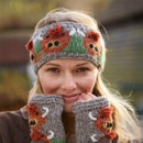 A woman outdoors wears a gray knitted headband and fingerless gloves, both adorned with colourful animal patterns. She smiles warmly, conveying joy. A woman outdoors wears a gray knitted headband and fingerless gloves, both adorned with colourful animal patterns. She smiles warmly, conveying joy.