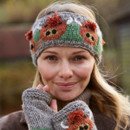 A smiling woman wears a hand-knitted headband and fingerless gloves with colourful owl designs. The background is blurred, giving an autumn feel. A smiling woman wears a hand-knitted headband and fingerless gloves with colourful owl designs. The background is blurred, giving an autumn feel.