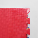Close-up of red interlocking floor mat corner showing textured, non-slip surface and puzzle-style edge, part of the Charlies multicoloured mat set.
