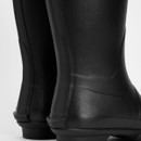 Rear view detail of a black Barbour wellington boot highlighting the textured rubber upper and reinforced heel.