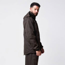 Side profile of a man modelling a dark brown waterproof jacket with a longer back hem.