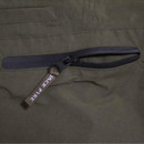 Close-up of a horizontal zipped pocket on olive green outdoor trousers with a branded zip pull.