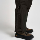 Close-up of dark brown outdoor trousers showing the zipped lower-leg opening over hiking boots.