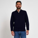 Man wearing a navy blue quarter-zip knitted jumper layered over a checked shirt with blue jeans.