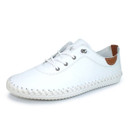 Angled view of white leather lace-up trainer shoe featuring metal eyelets, tan heel accent and hand-stitched white sole on a white background.