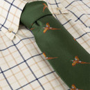 Close-up of a green necktie featuring a repeating flying game bird motif, styled with a cream checked shirt.