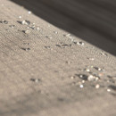 Water droplets on a textured fabric surface, with sunlight glinting off them.