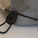 Close-up of a grey fabric with a black cord lock on a drawstring.