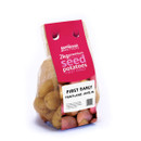 Bag of 2kg Scottish seed potatoes labelled "First Early Pentland Javelin" in a mesh bag with pink branding. The mood is fresh and agricultural.