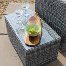 Outdoor scene with two wine glasses and a wooden board with green grapes on a wicker table. The sunny setting conveys a relaxed, leisurely vibe.