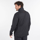 Man in black jacket facing away, looking over shoulder. Jacket has a high collar and appears casual. Background is plain white, suggesting a studio setting.