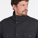 A close up of a man wearing a navy jacket which buttons around the neck