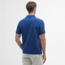 Man facing away, wearing a blue polo shirt and beige pants against a plain white background. The scene conveys a casual, relaxed atmosphere.