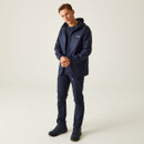 Young man wearing a navy blue hooded jacket and matching trousers, standing casually against a neutral background, conveying a relaxed and confident vibe.