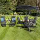 Outdoor patio set on a lush green lawn, featuring cushioned chairs, a table with drinks under a large umbrella, conveying a relaxing ambiance.