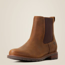 Brown leather Chelsea boot with dark elastic side panels, visible stitching, and a low stacked heel, set against a plain beige background. Rugged, classic style.