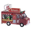 A festive hot chocolate food truck with a red exterior, decorated with greenery, offering drinks like hot cocoa and spiced lattes.