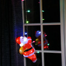 A climbing santa on a window hanging from a rope of multicoloured string lights