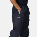 A person wears navy blue waterproof trousers with hands in pockets, featuring an elastic waistband. The fabric appears durable, conveying utility and comfort.