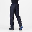 Person wearing dark navy, lightweight waterproof trousers and black shoes with blue soles, walking on a plain white background.
