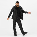 Man wearing a black waterproof jacket and pants, posing confidently against a white background. The attire suggests a focus on outdoor activities.