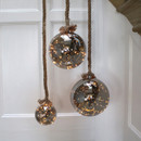 Three glass ball LED rope lights, hung against a white wall, creating a cosy, illuminated décor.