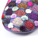 Close-up of the toe area of a slipper showcasing a colourful knitted pattern with raised fuzzy polka dots. The design includes red, purple, green, pink, and cream tones on a purple sole, giving a textured and cosy appearance.
