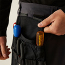 Close-up of multi-pocket tool holster on work pants holding screwdrivers and pliers, featuring heavy-duty fabric compartments, reinforced stitching, and easy-access storage design.