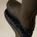Close-up of Le Chameau men’s Wellington boots showing the textured green rubber uppers and deep black lugged tread soles.