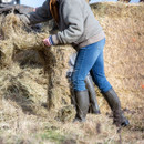 Le Chameau women’s green wellington boots worn outdoors while working with hay, ideal for country and farm use.