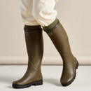 Le Chameau women’s green Giverny wellington boots worn with trousers, showing the tall rubber design and treaded soles.