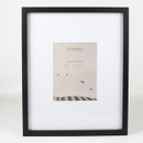 Black rectangular photo frame with white mount and central aperture, shown against a plain light background.
