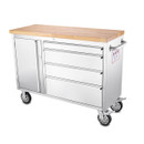 Stainless steel kitchen trolley with wooden worktop, cupboard, drawers and castor wheels on a plain background.
