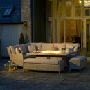Cosy outdoor patio setup with sectional sofa and lit fire pit table at dusk.