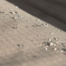 A close up view of a grey garden furniture cover with water droplets running off