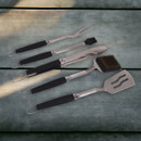 Five barbecue tools arranged on a grey surface, including tongs, spatula, fork, basting brush and grill brush.