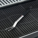 Barbecue fork with a black handle resting on cast iron grill grates.