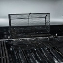 Rotisserie basket opened to show the mesh cage and central spit rod inside an open barbecue.