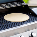 Ceramic pizza stone heating on a barbecue grill