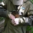 Person in a jacket and cap opening a chest pocket