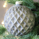 A close up view of a grey geometric bauble with a diamond pattern, hanging from a Christmas tree.