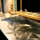 A close up of a Champagne Feathered Christmas Garland on a mantelpiece with a mirror in the background.