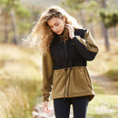Person in a teak jacket and black trousers standing outdoors with trees in the background.